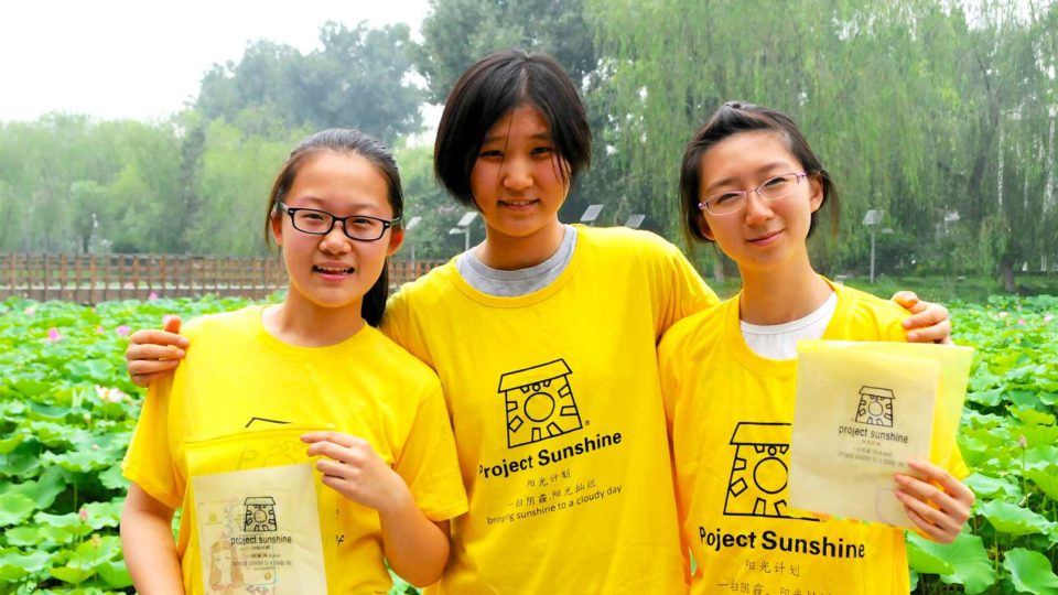 Volunteers from Project Sunshine China hold up arts and crafts kits