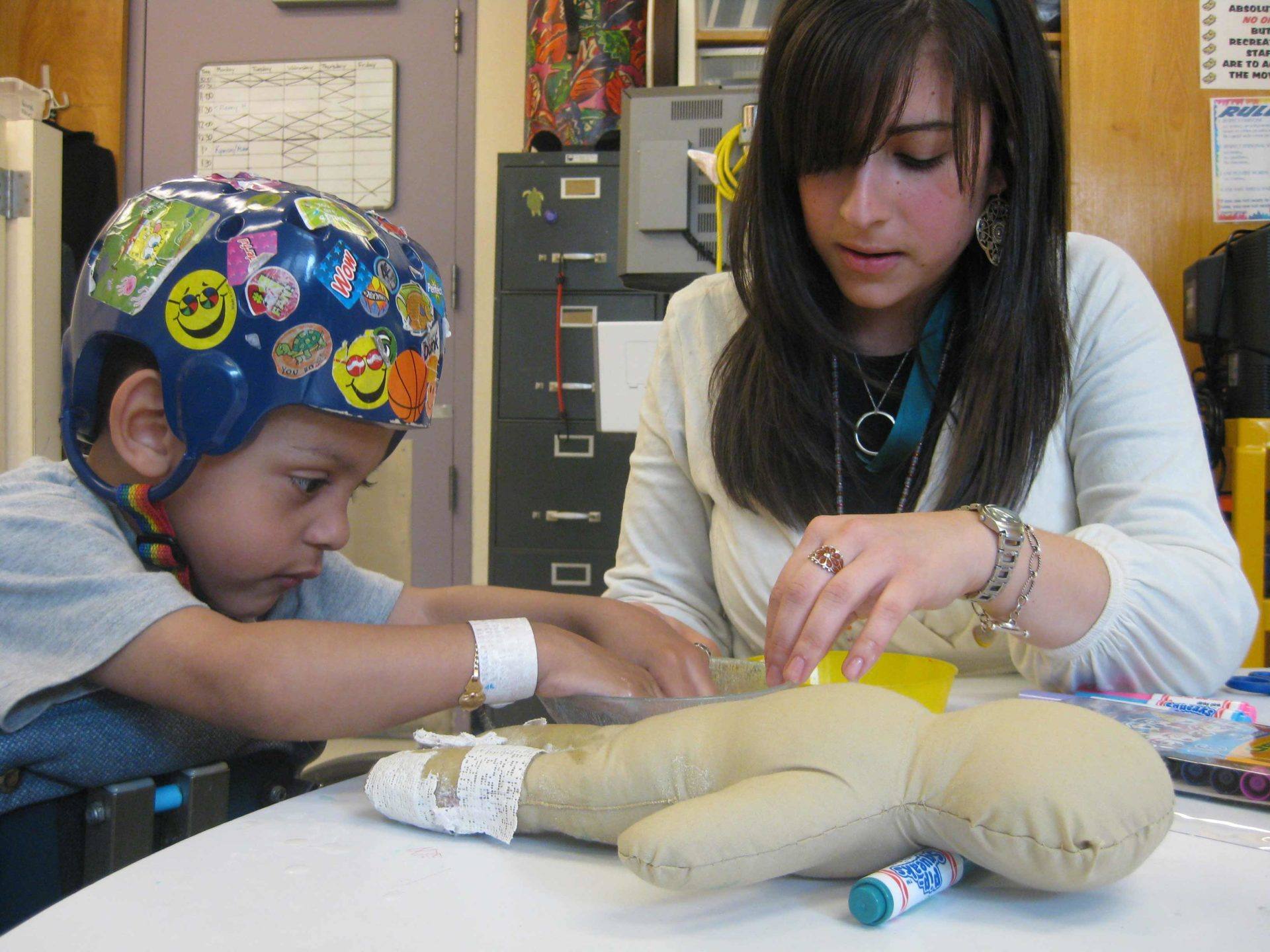 Medical facility staff member using a Surgi Doll to explain a pediatric patients upcoming procedure